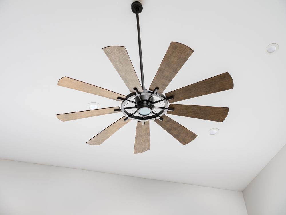 A ceiling fan with wooden blades hanging from the ceiling.